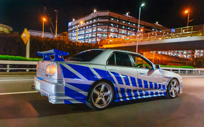 Car drifting on Tokyo street at night during Fast & Furious Tokyo Drift III Experience.