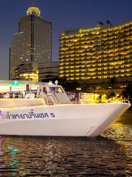 Chao Phraya Princess cruise ship docked near illuminated Bangkok skyline at night.