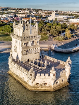 Belém Tower in Lisbon, Portugal, surrounded by water with cityscape in the background.