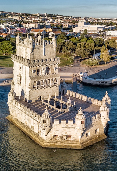 Belém Tower in Lisbon, Portugal, surrounded by water with cityscape in the background.