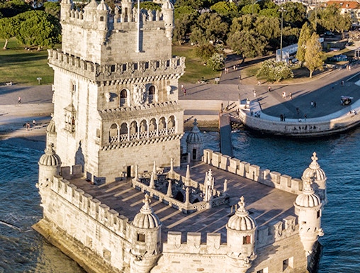 Belém Tower in Lisbon, Portugal, surrounded by water with cityscape in the background.