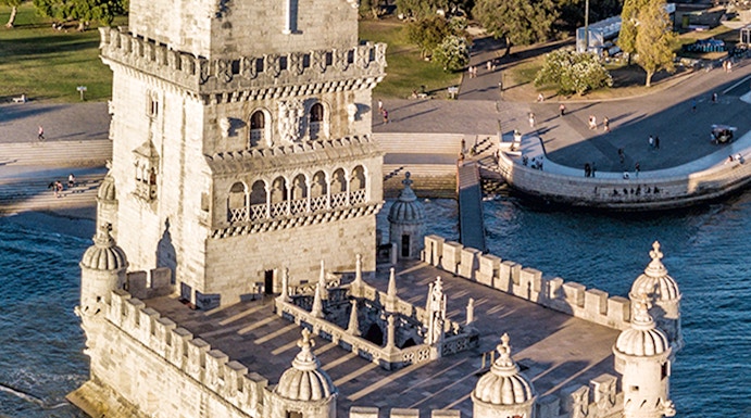 Belém Tower in Lisbon, Portugal, surrounded by water with cityscape in the background.