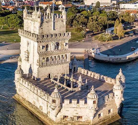 Belém Tower in Lisbon, Portugal, surrounded by water with cityscape in the background.