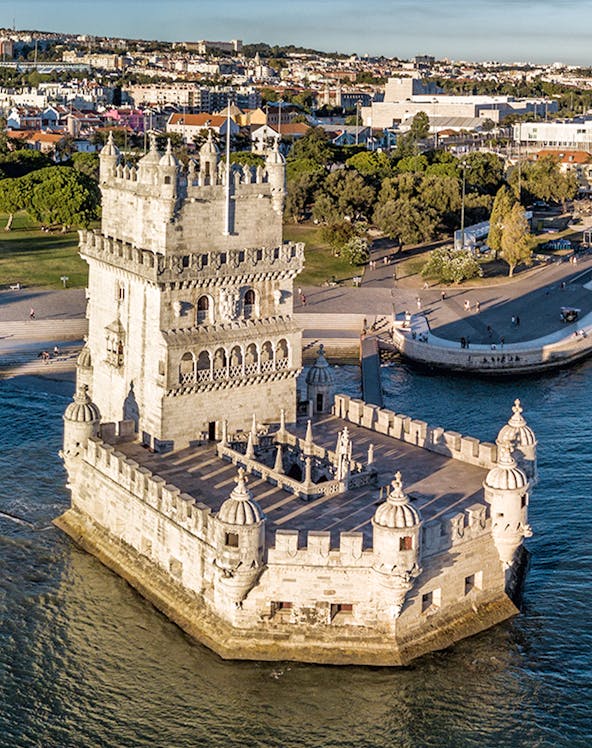 Belém Tower in Lisbon, Portugal, surrounded by water with cityscape in the background.