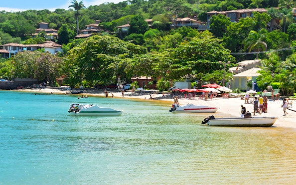 Boats and people enjoying Praia dos Ossos beach in Armação dos Búzios, Brazil.