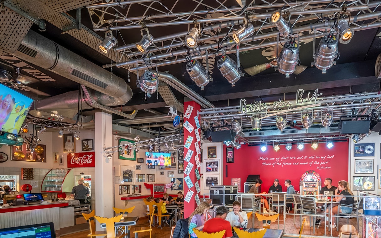 Indoor dining area at Europa-Park with guests seated, vibrant decor, and stage lighting.