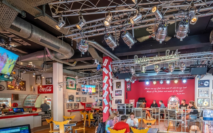 Indoor dining area at Europa-Park with guests seated, vibrant decor, and stage lighting.