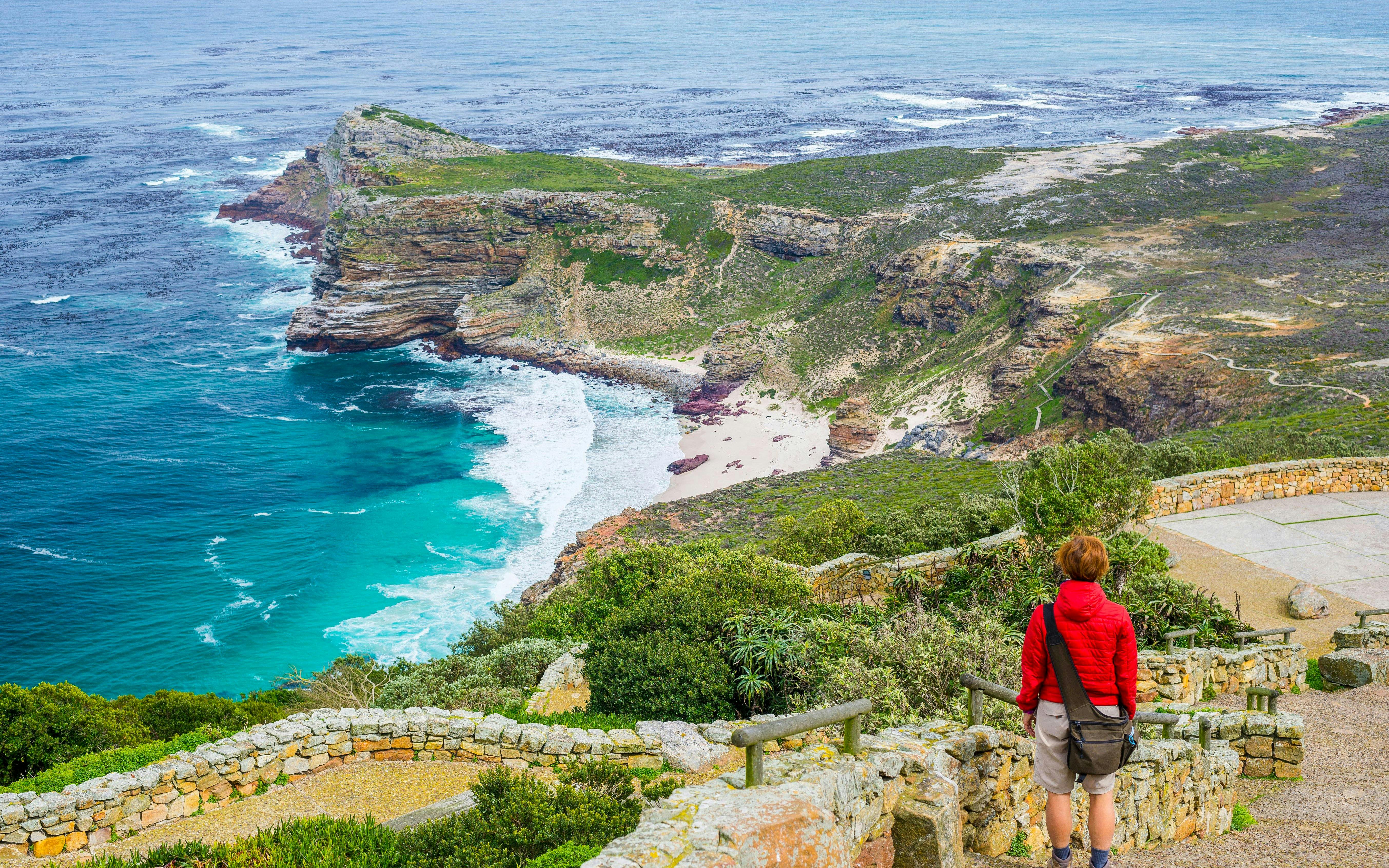Tourist hiking at Cape Point, viewing Cape of Good Hope coastline.