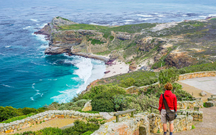 Tourist hiking at Cape Point, viewing Cape of Good Hope coastline.