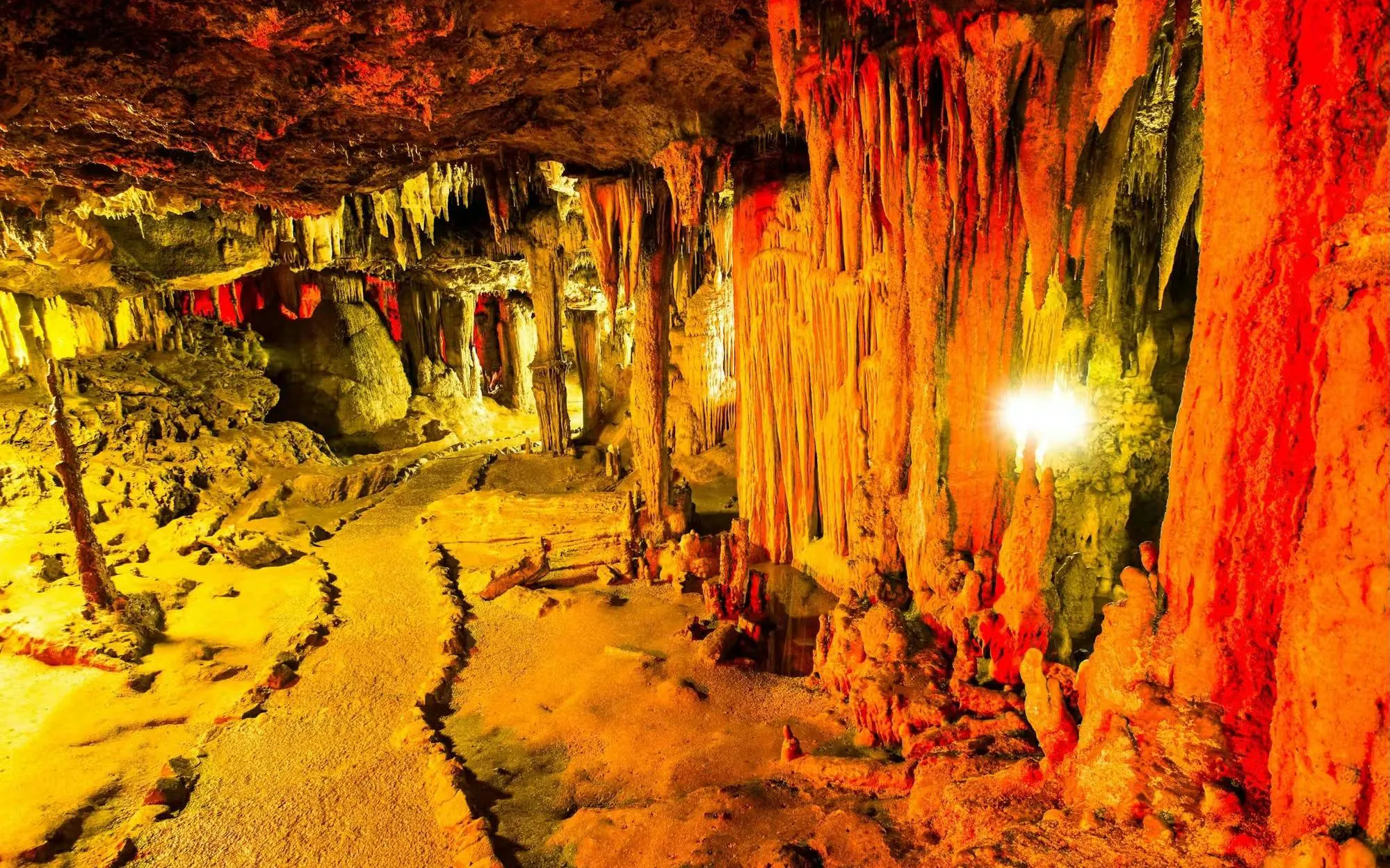 Stalactites and stalagmites in illuminated chamber of Nerja Caves, Spain.