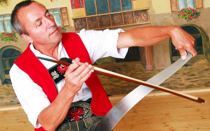 Man playing musical saw at Tyrolean Evening Folk Show, Austria.