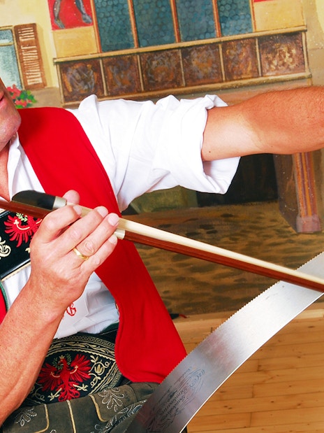Man playing musical saw at Tyrolean Evening Folk Show, Austria.