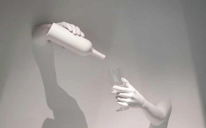Hands pouring wine into a glass, representing The Wine Experience.