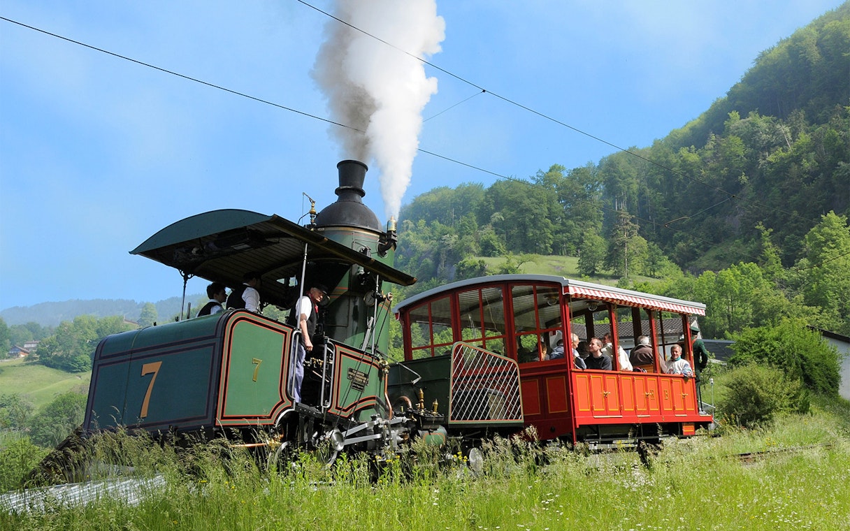 Vintage steam train ascending Mount Rigi with passengers enjoying scenic views.