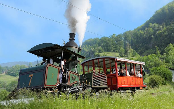 Vintage steam train ascending Mount Rigi with passengers enjoying scenic views.