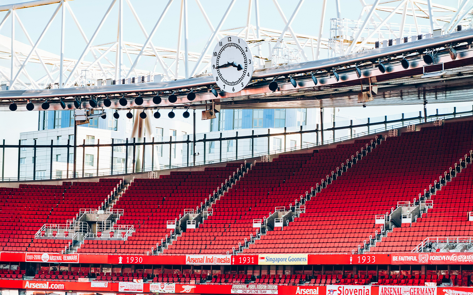 Red seating and iconic clock inside Emirates Stadium, London.