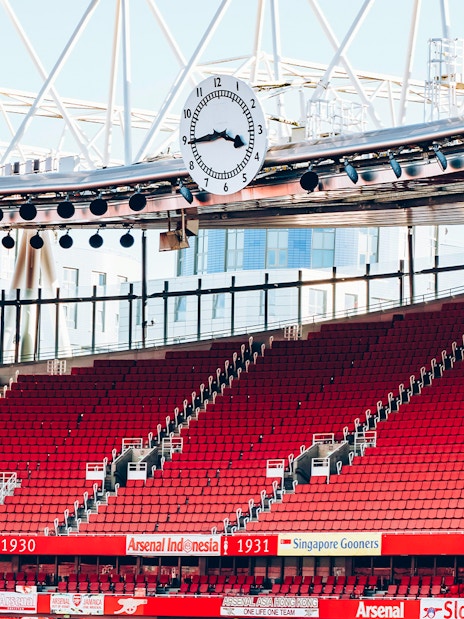 Red seating and iconic clock inside Emirates Stadium, London.