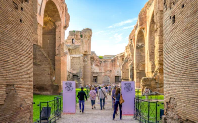 Tourists walking through ancient ruins at Baths of Caracalla, Rome.