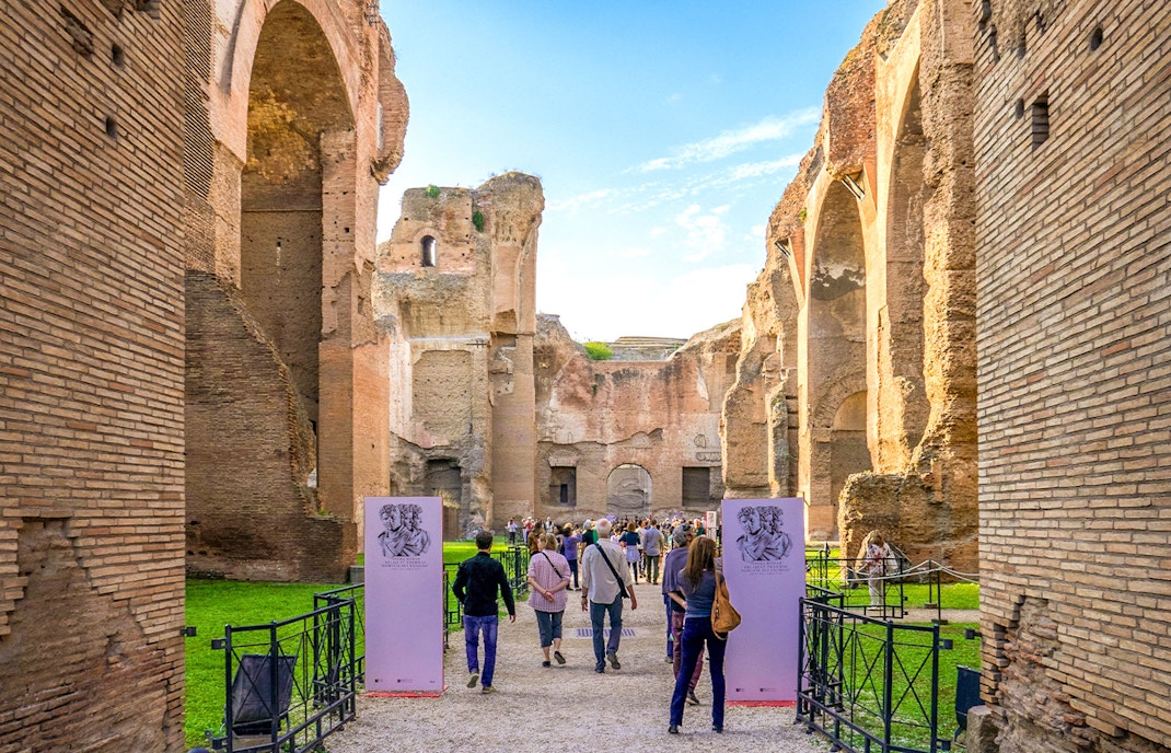 Tourists walking through ancient ruins at Baths of Caracalla, Rome.