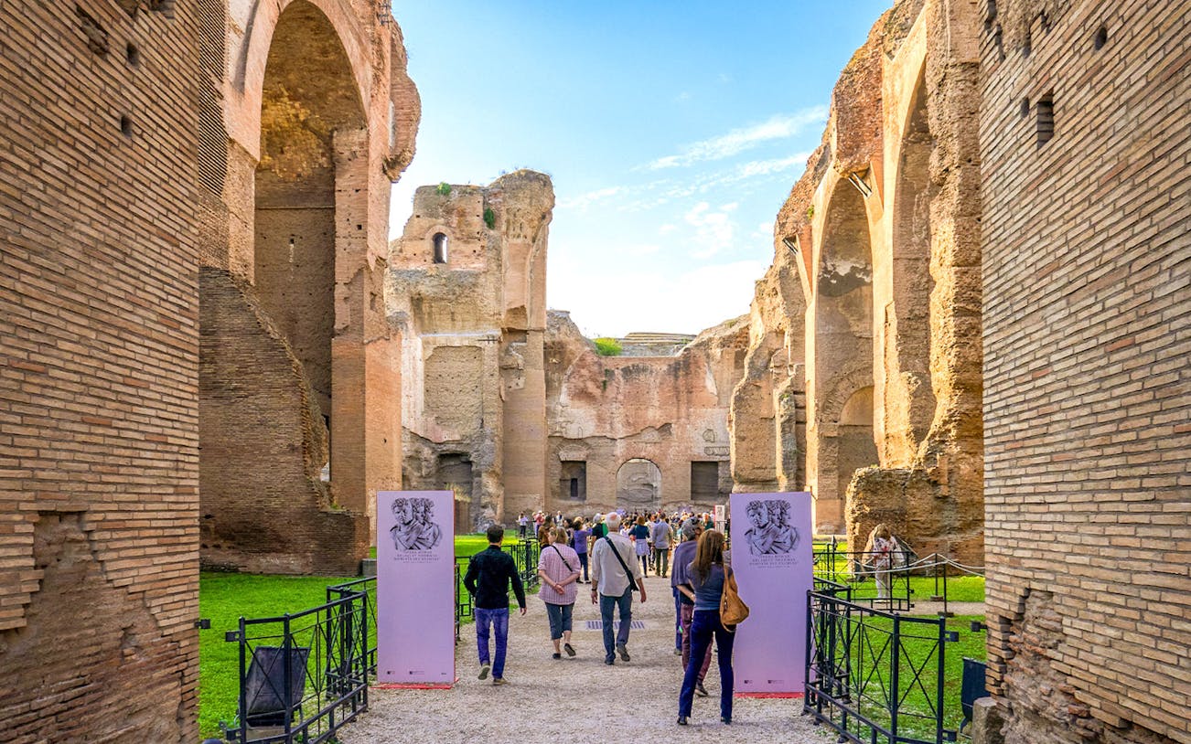 Tourists walking through ancient ruins at Baths of Caracalla, Rome.