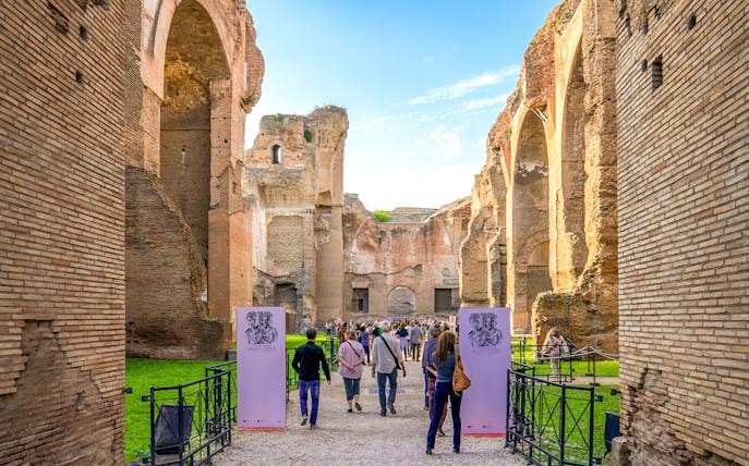 Tourists walking through ancient ruins at Baths of Caracalla, Rome.