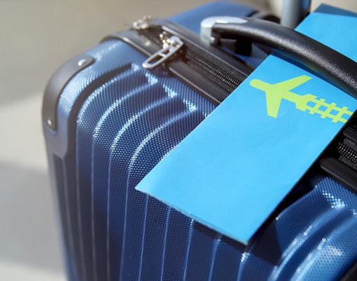 Blue suitcase with a boarding pass at an airport.