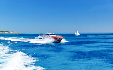Ferry and sailboat on turquoise waters near Rottnest Island, Western Australia.