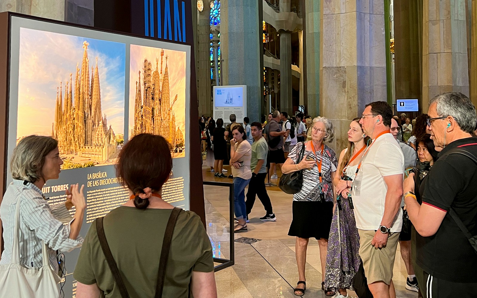 Tour guide explaining architecture to tourist at Sagrada Familia, Barcelona.