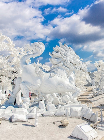 White dragon sculpture at Frost Magical Ice of Siam, Thailand, under a blue sky.