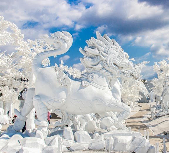 White dragon sculpture at Frost Magical Ice of Siam, Thailand, under a blue sky.