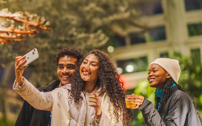 Visitors enjoying drinks and taking a selfie at New York Botanical Gardens.
