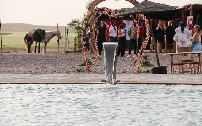 Safari lunch setup with pool and camels in Agafay desert.