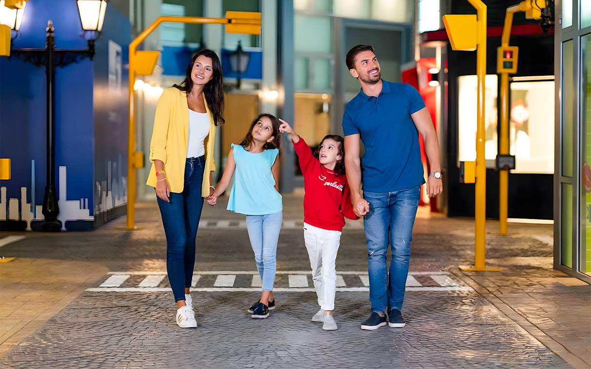 Family walking through KidZania Abu Dhabi, children pointing at attractions.