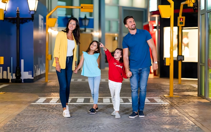 Family walking through KidZania Abu Dhabi, children pointing at attractions.
