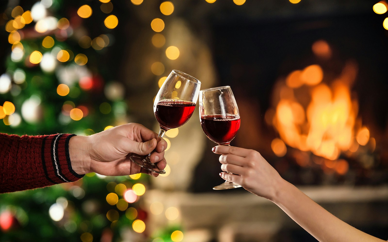 Couple celebrating christmas with red wine in glasses.