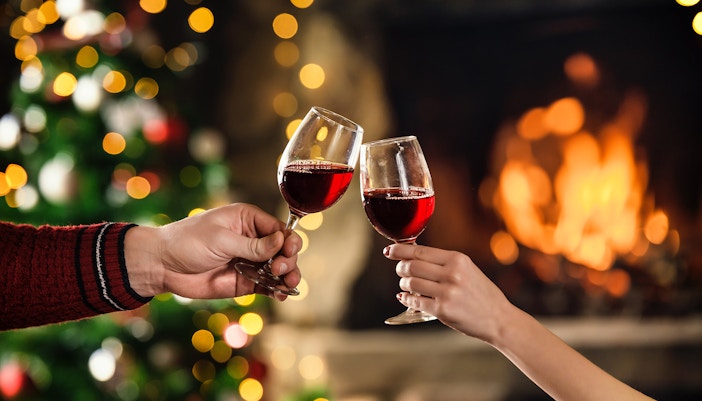 Couple celebrating christmas with red wine in glasses.