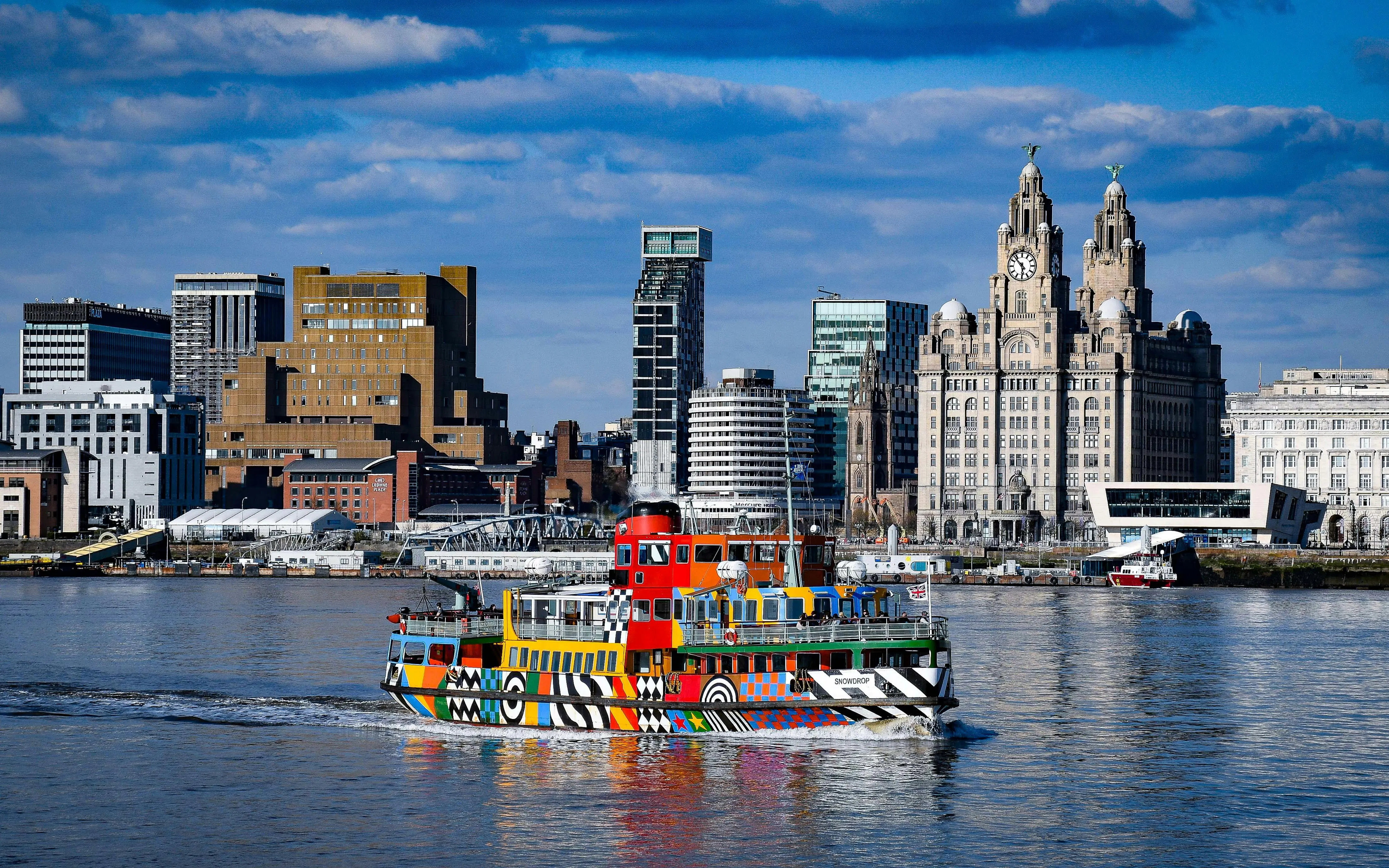 Colorful ferry on the River Mersey with Liverpool skyline in the background.