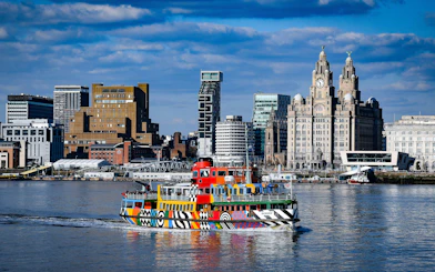 Colorful ferry on the River Mersey with Liverpool skyline in the background.