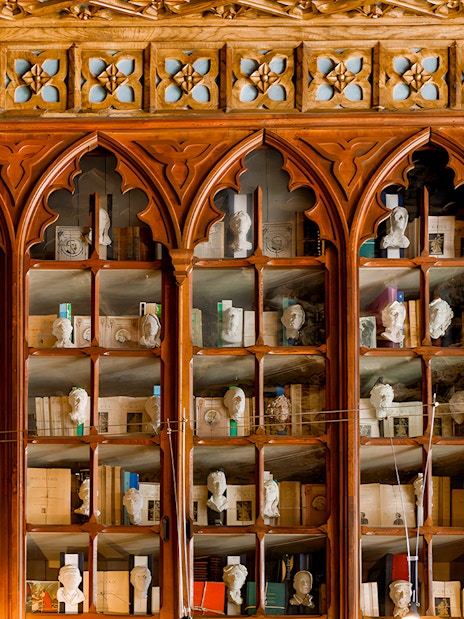 Lello Library ornate wooden bookshelves with busts and books, Porto, Portugal.