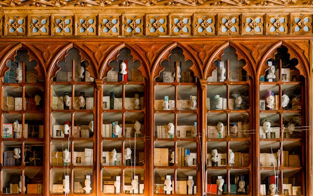 Lello Library ornate wooden bookshelves with busts and books, Porto, Portugal.
