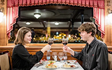 Couple toasting with wine on Danube dinner cruise at night.