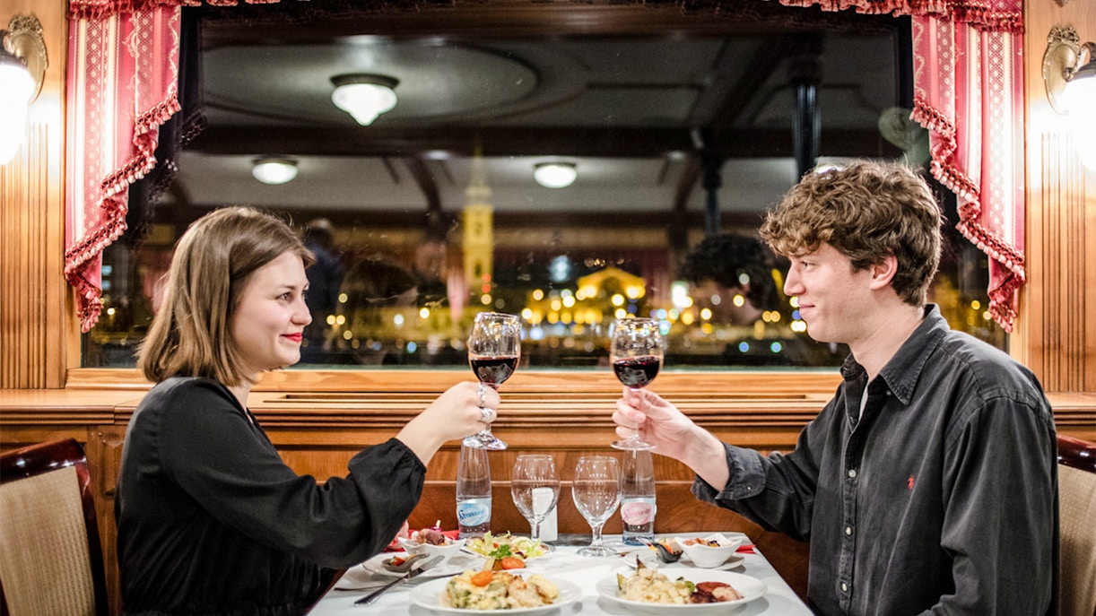 Couple enjoying wine on a Danube River dinner cruise in Budapest at night.