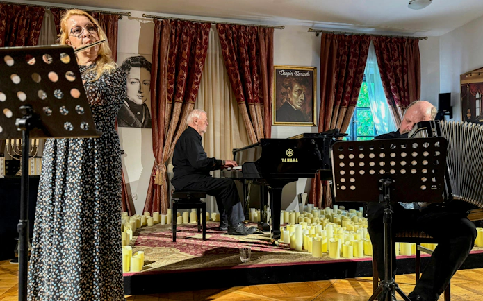 Klezmer musicians performing in Krakow concert hall with piano and flute.