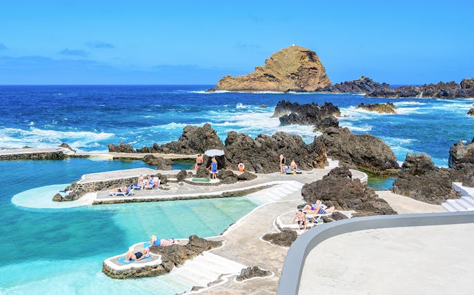 Visitors enjoying Porto Moniz lava pools with ocean view, Madeira.