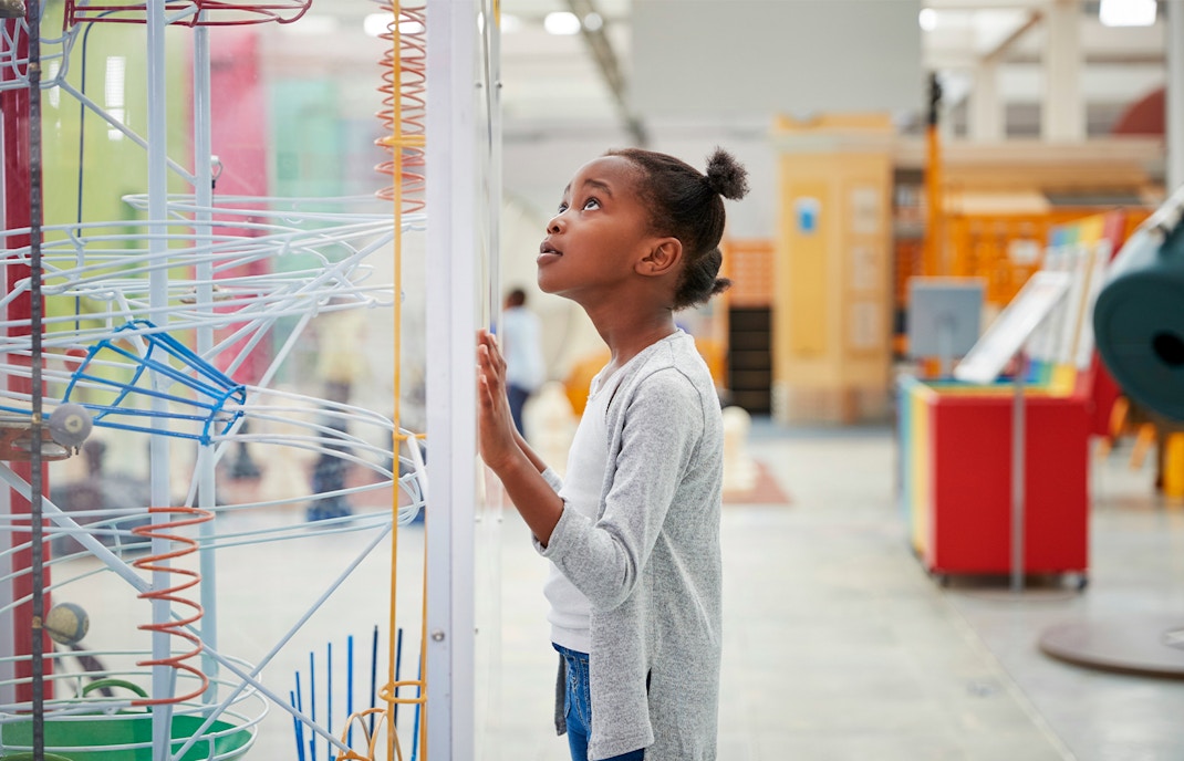 Young girl observing interactive science exhibit at museum.
