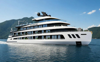 Luxury cruise ship on Ha Long Bay with mountainous backdrop.