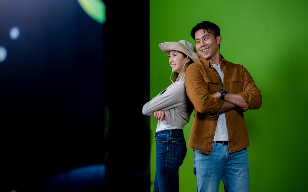 Couple posing back-to-back in front of green screen at Enchanted Forest.