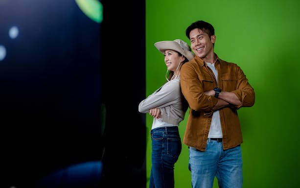 Couple posing back-to-back in front of green screen at Enchanted Forest.