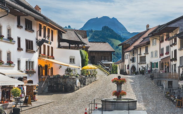 Gruyères village street with historic buildings and mountain backdrop, part of guided tour from Basel.