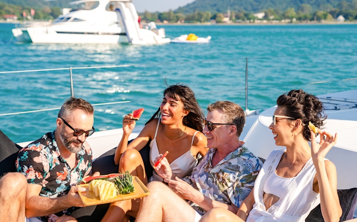 Friends enjoying fresh fruit on a catamaran sailing trip.
